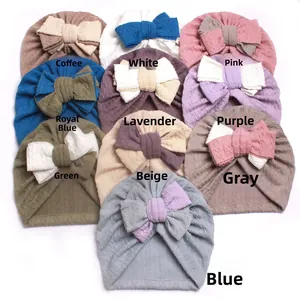 Detail showing various colors of soft knitted baby beanies with oversized decorative bows