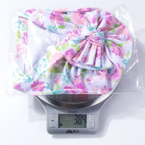 Lightweight floral baby turban with large bow weighing approximately 38.4g including packaging