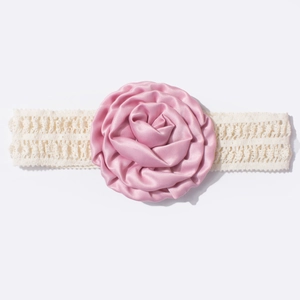 Détail d'une rose en satin rose et d'un bandeau pour bébé en dentelle crème élastique