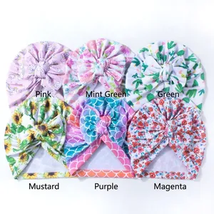 Detail showing various colorful floral and unicorn print patterns on baby bow beanies