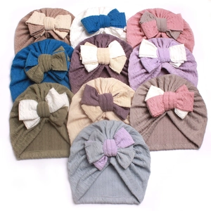 Macro detail of infant knit hats featuring cable knit texture and large double bows