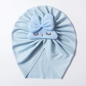 Detail of light blue ribbed knit baby hat featuring cute plush bow and eyelash embroidery