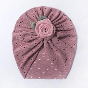 Dettaglio del cappello a turbante per neonato con ricamo traforato e rosa in tessuto