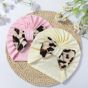 Baby turban hats in pink and beige colors featuring large leopard print bows and ribbed fabric