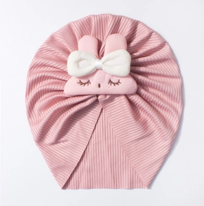Detail of pink ribbed baby hat with cute rabbit patch and large white bow decoration