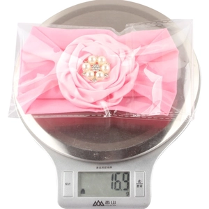 Pink ribbon flower baby headband with pearls and rhinestones on a digital scale weighing 16.9g