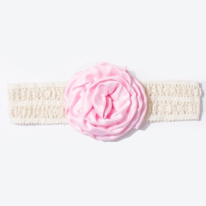 Détail d'une fleur de rose en satin rose sur un bandeau de bébé en dentelle élastique blanche