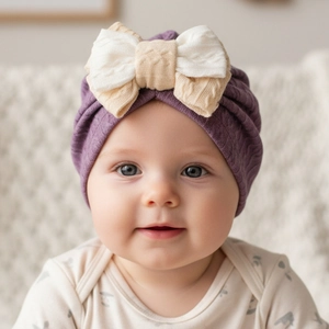 Close-up of baby turban hat with a large textured knit bow in purple and beige