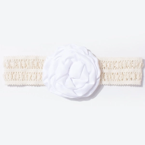 Détail d'un bandeau en dentelle pour bébé avec une grande fleur en tissu blanc et pétales