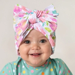 Close-up of floral print baby headband featuring a large bow and textured elastic fabric