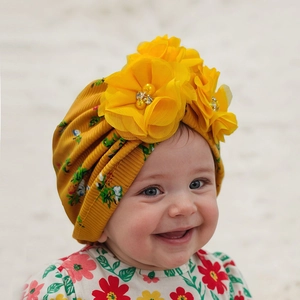 Detail of yellow ribbed baby hat with three large chiffon flowers and pearl accents