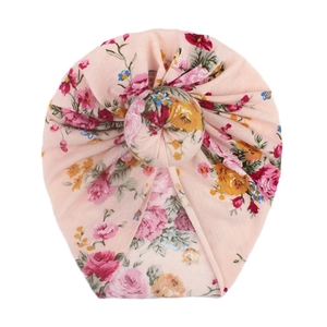 Dettaglio del turbante per neonata rosa con fantasie di rose rosse e nodo a forma di ciambella