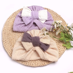 Soft baby turban hats with double-layered contrast bows on a natural woven mat