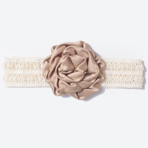 Détail d'une rose en satin champagne sur un bandeau élastique en dentelle pour bébés