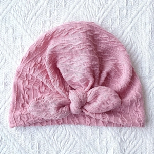 Detail of pink ribbed baby turban hat with large bow and cable knit texture