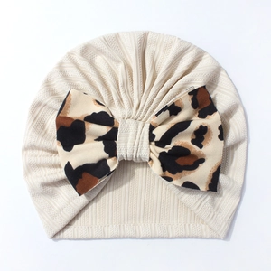 Detail of baby turban hat showing ribbed fabric texture and leopard print bow