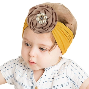 Detail of yellow nylon baby headband with a large brown fabric flower and pearl center