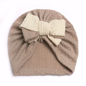Close-up of the textured cable knit fabric and soft cream bow on this infant turban hat
