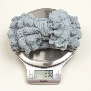 Gray textured elastic baby headband weighing 29.8g on a digital scale closeup