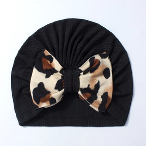 Detail of baby black ribbed knit hat featuring a large leopard print bow on white background