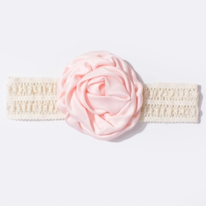 Vue détaillée d'une rose en satin rose sur un bandeau en dentelle blanche pour bébé