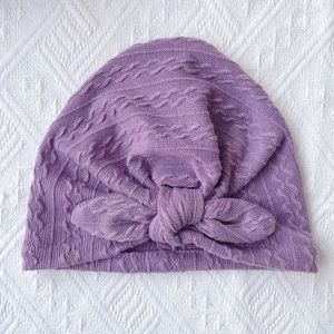 Detail of purple ribbed knit baby hat with rabbit ear knot and soft braided texture