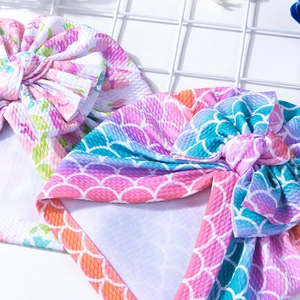 Detailed view of baby turban hats with floral and scale patterns and big bows