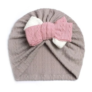 Detail of baby turban hat with oversized two-tone knit bow and cable texture