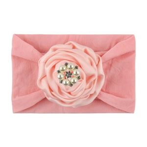 Pink elastic nylon baby headband featuring a large satin rose flower with pearl and crystal center
