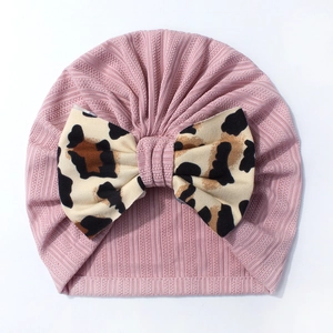 Detail of baby pink ribbed knit turban hat featuring a large leopard print bow