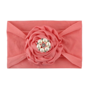 Close-up of pink elastic baby headband featuring a large fabric rose with pearls and rhinestones