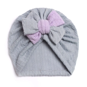 Detail of grey ribbed knit baby hat featuring a double-layered purple bow decoration