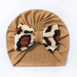 Detail of baby turban hat featuring a leopard print bow and caramel ribbed fabric