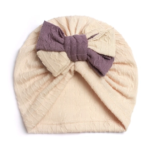 Detailed close-up of soft ribbed knit baby turban hat with a purple and cream bow