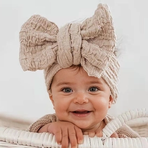 Close-up of a baby girl wearing a large beige textured cotton bow headband