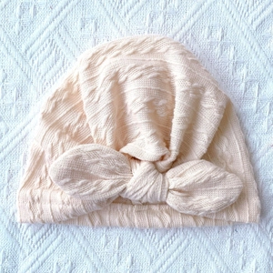 Detail of soft apricot ribbed knit baby turban hat with a large bow decoration