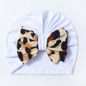 Detailed view of white ribbed knit baby turban featuring a large leopard print bow accent