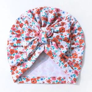 Floral print baby turban hat with large decorative bow on a soft cotton knit fabric