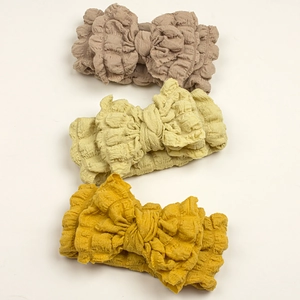 Set of three textured bubble fabric baby headbands with large bows in earthy tones
