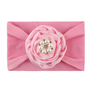 Detail view of pink nylon baby headband featuring a satin flower with pearl and rhinestones