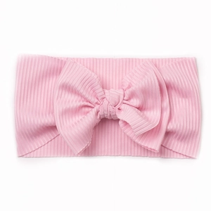 Détail d'un bandeau rose pour bébé en tissu côtelé avec un grand nœud double élégant