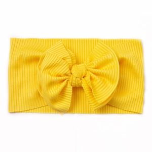 Détail d'un bandeau bébé en tissu côtelé jaune vif orné d'un grand nœud décoratif souple