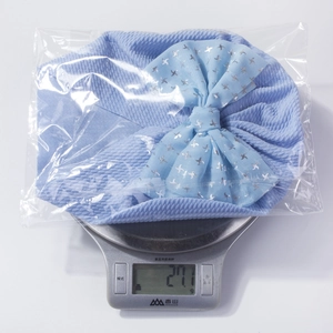 Macro detail of breathable light blue waffle knit baby hat with a large bow weighing 27.1g