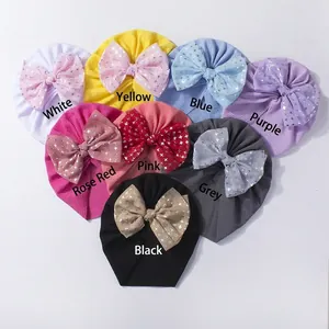 Flat lay of eight colorful infant bow turbans with shiny silver star patterns on fabric