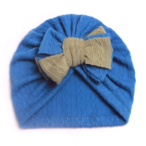 Close-up of blue knit baby turban hat with a large khaki bow and cable knit texture