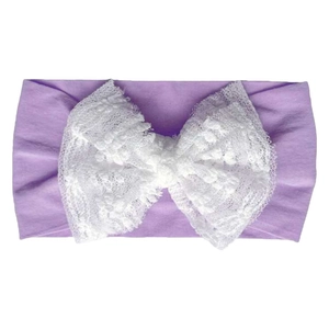 Detail showing the soft light purple fabric base and large white double lace bow for baby headband