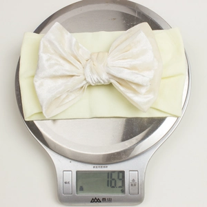 Détail montrant le bandeau léger de 16,9g en velours doré pour bébé sur une balance