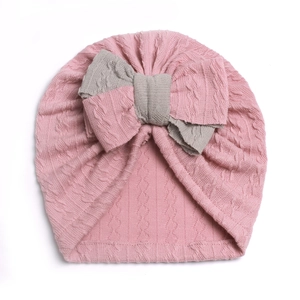 Detail of soft cable knit texture and gray bow on pink baby turban hat for infants