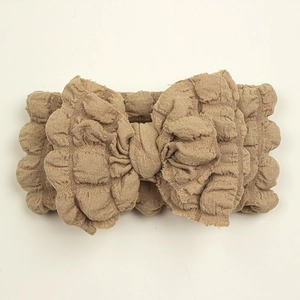 Detailed texture of baby headband with large camel bow made of elastic bubble fabric