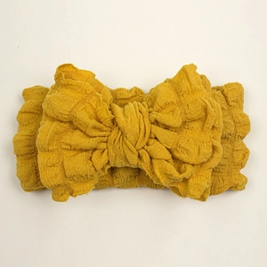 Mustard yellow stretchy bow headband for babies featuring soft crinkle bubble fabric
